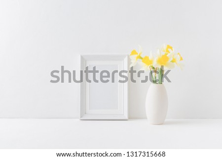 Home interior with decor elements. Mockup with a white frame and yellow daffodils in a vase on a light background