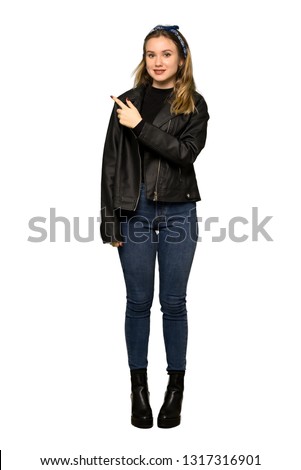 A full-length shot of a Teenager girl with leather jacket pointing to the side to present a product on isolated white background