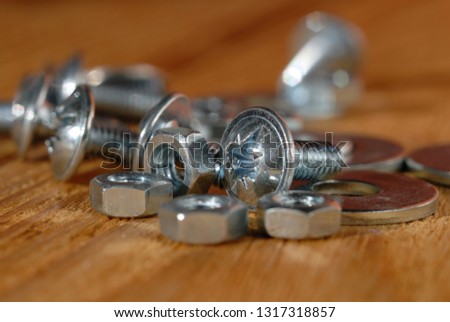 Screws and nuts for home workshop on a wooden surface closeup. Shallow depth of field