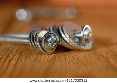 Screws with washers for home workshop on a wooden surface closeup. Shallow depth of field
