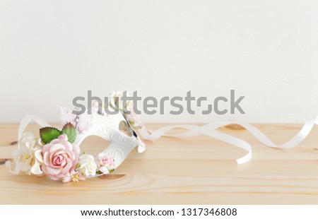 carnival party celebration concept with elegant white mask over wooden table