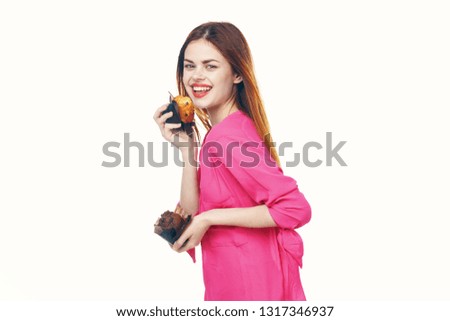 Cheerful pretty woman in a pink sweater with cupcakes in their hands