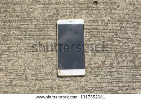 Broken screen smartphone falls down on the concrete floor