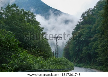 Misty mountain road in high mountains. High mountain road is being covered with fog.