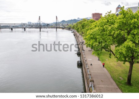 View of 
Hawthorne Bridge and Park along willamette river in Portland, Oregon. People walking in the park
