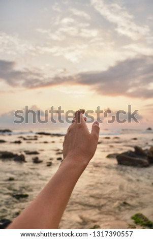 Girl reaches out to the clouds. Girl pulls her hand to the sea. Sri-lanka.