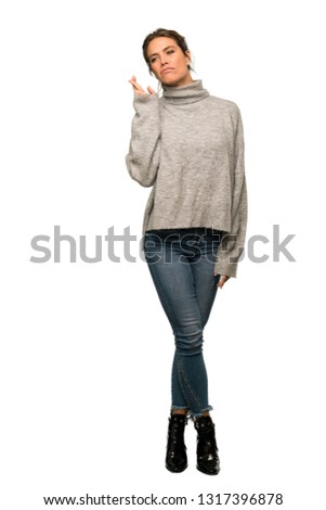 A full-length shot of a Blonde woman with turtleneck with fingers crossing and wishing the best over isolated white background