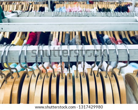 Row of wooden cloth hangers hanging on white metal clothes. 