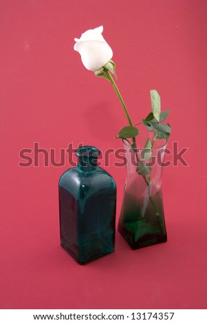 White rose in a vase and green bottle.