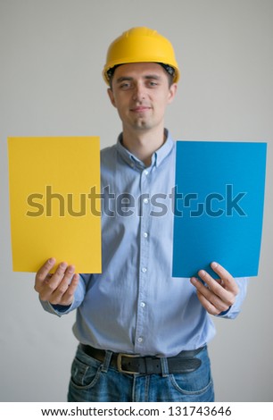 A man in a helmet holding sheets of colored paper
