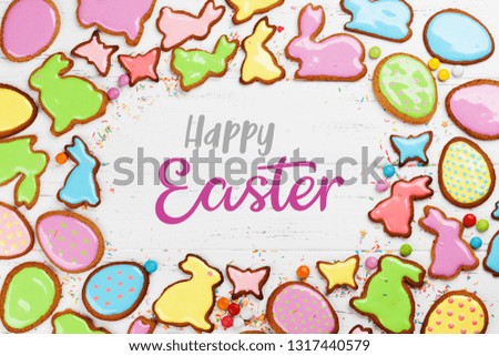 Easter greeting card with colorful gingerbread cookies. Top view on wooden table with space for your greetings