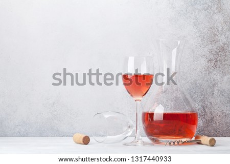 Rose wine in glass and decanter on wooden table. In front of stone wall with space for your text
