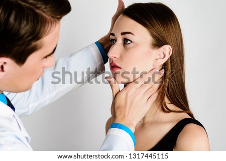 The doctor, a man, put his hand on the patient's neck to conditionally separate the lower jaw from the neck, to assess the severity of the profile Royalty-Free Stock Photo #1317445115