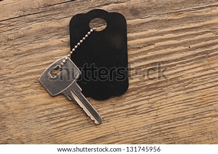 Blank tag and a key on wooden background