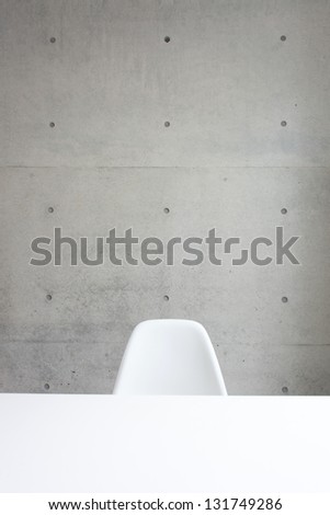 white chair and table against concrete wall