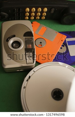 old radio telephone, vintage analog photo camera, two retro diskette and CD player - obsolete, outdated objects lie on green background. 