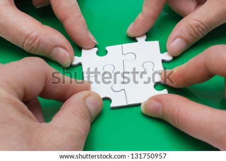 Close up of four people' hands with puzzle