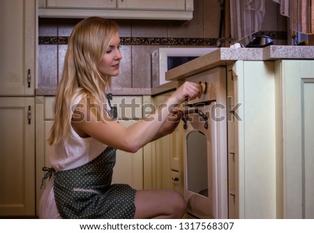 Blonde girl preparing dinner in the oven. Home kitchen background