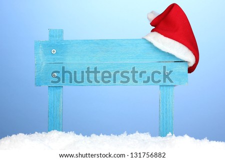 Wooden road sign with Santa hat on blue background