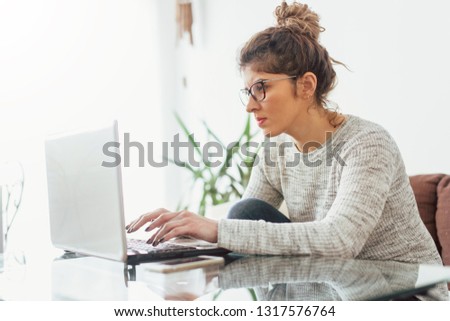 Young woman working at her home. She working at lap top Royalty-Free Stock Photo #1317576764