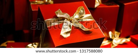 Red gift box with ornaments and ribbons on red holiday background. Merry christmas card. Christmas decorations