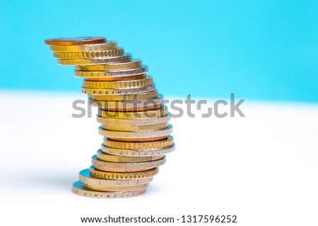 Coins stacked on each other in different positions on a blue and white background. Copy space for text