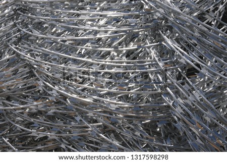 Coils of silver razor wire, shiny metallic background 