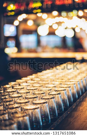 Rows of clean empty  beer or water  glasses turn upside down on counter bar
with bokeh background
