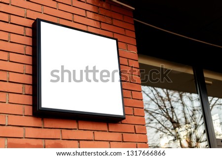 Blank square signboard, business light up sign mock up mounted on the brick wall of a small business workshop store