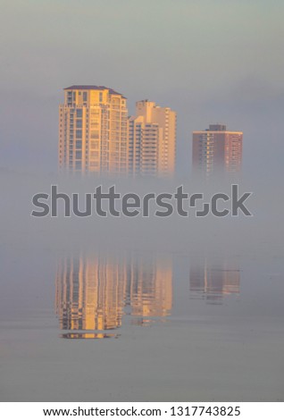 Reflections of the city through the fog of the sunrise.