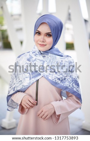 Portrait of a beautiful Asian woman  wearing beige color dress and pants with hijab in a real environment. Muslim female hijab fashion portraiture concept.