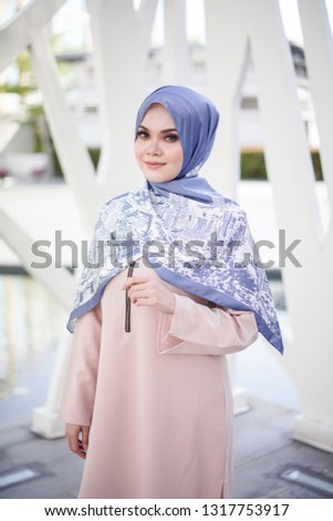 Portrait of a beautiful Asian woman  wearing beige color dress and pants with hijab in a real environment. Muslim female hijab fashion portraiture concept.