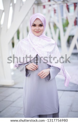 Portrait of a beautiful Asian woman  wearing grey color dress and pants with hijab in a real environment. Muslim female hijab fashion portraiture concept.