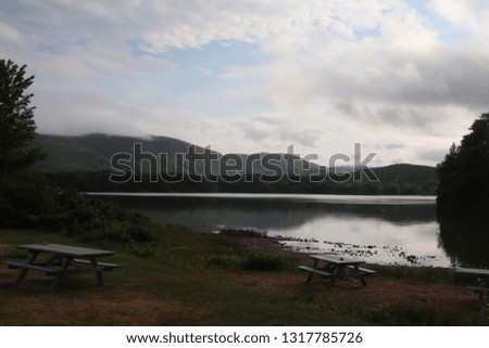 A view of a lake where you can see the beach and a picnic table early in the morning 