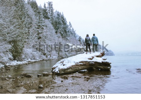 Couple looking at mountain lake from log on water