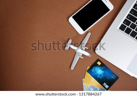 Smartphone, laptop, credit cards and toy plane on color background, flat lay with space for text. Travel agency