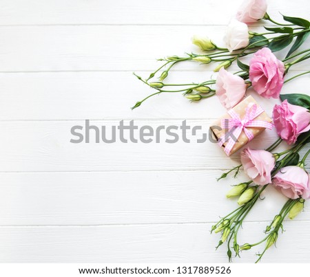 Fresh pink eustoma flowers and gift box on wooden background