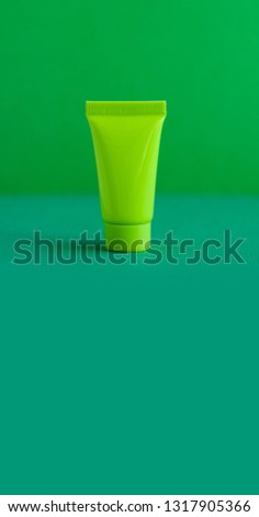Minimal cosmetic shampoo package design. Green cosmetic tube on greenery background. Blank plastic container simple packaging template. shallow depth of field, copy space.