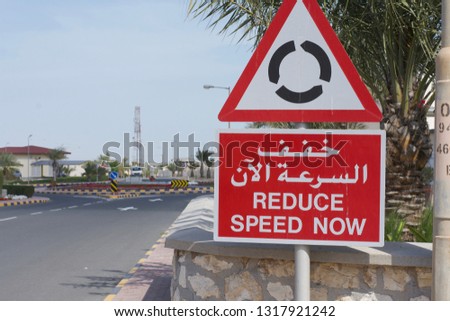 Roundabout road sign with Middle East. English and Arabic writing . Reduce speed now. Copy space. 