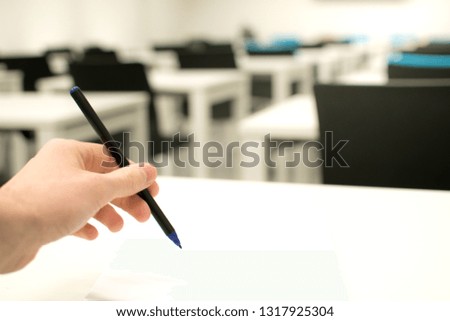 Classroom empty. High school or university student holding pen writing on paper answer sheet. Exam test room
