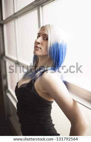 Portrait of a beautiful young woman with blue hair and a very short black dress.