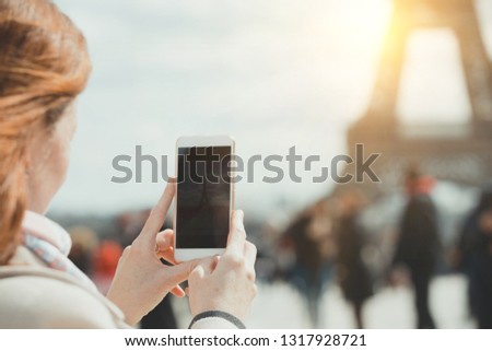 Girl takes pictures of a Eiffel Tower on a smartphone  in Paris. France 
