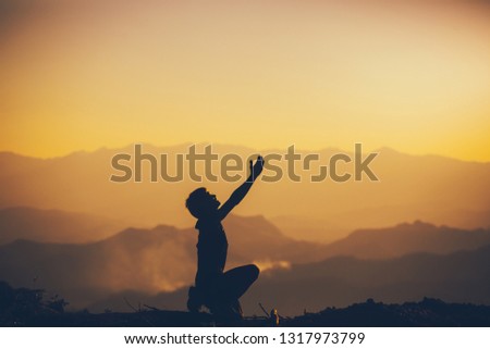 Man sitting and worshipping God at sunset background. christian silhouette concept.