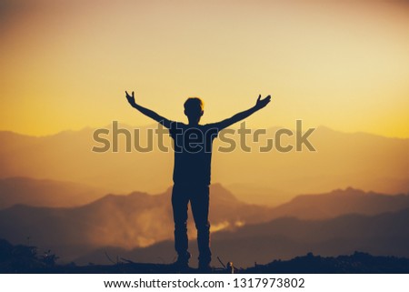 Man standing with lift hands for worshipping God at sunset background. christian silhouette concept.