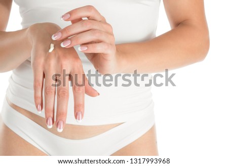 Woman applying hand cream, white background, closeup and french manicure. Cropped female body in white top and panties. Skin and body care, natural treatment concept