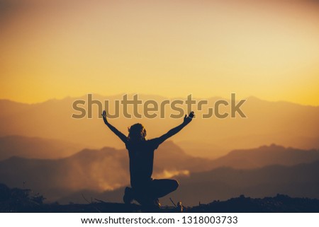 Man sitting and lift two hands for worshipping God at sunset background. christian silhouette concept.