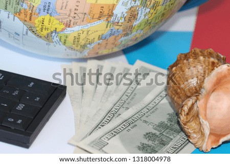 Planning a trip around the world. On holiday with the whole family. In the photo: plane, money, shell, calculator, pen and notebook. Financial calculation of traveling with the whole family.