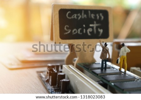 miniature mini  figures walking on Integrated Circuit straight to Cashless Society black board.Concept of cashless society for Credit card,Mobile phone, hardware,  technology for new financial.