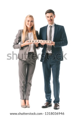 smiling businesspeople in suits holding alphabet cubes with equality word, isolated on white