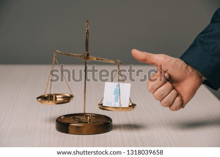 partial view of businessman showing thumbs up near scales of justice and male signs, gender stereotypes concept 